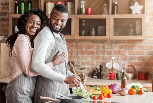 Thankful african american wife hugging her husband from behind at kitchen, making dinner together, copy space photo
