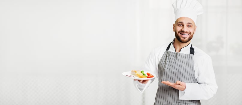 Happy Chef Man Holding Plate With Cooked Grilled Salmon Presenting Dish Standing In Kitchen Indoor. Selective Focus photo