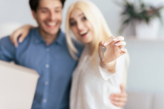 A happy couple stands together, the woman holding keys to their new home. photo