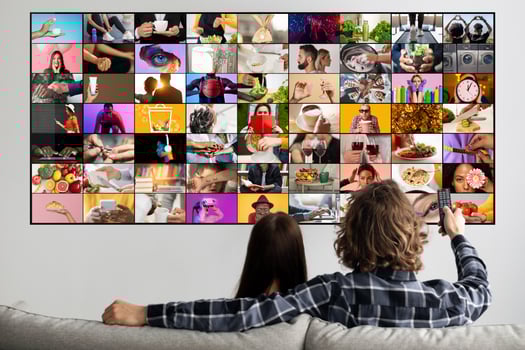 A couple is sitting on a couch, watching television. The screen is displaying multiple channels, each with a different image or . The couple is relaxed and enjoying their time together. photo