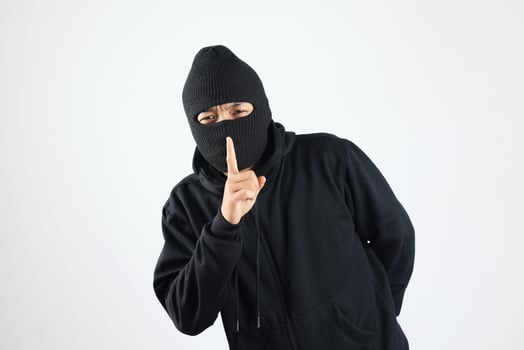 Thief in Black Balaclava Holding Fingers on Lips, Making Hush Sign photo