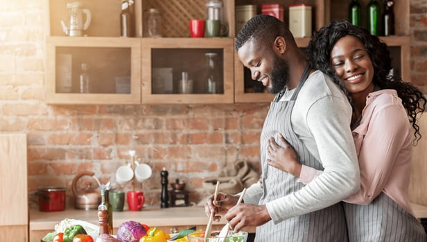 Grateful african american wife embracing her husband from behind at kitchen, making dinner together, copy space photo