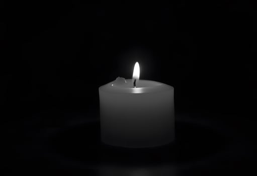 A single candle is lit in the dark photo