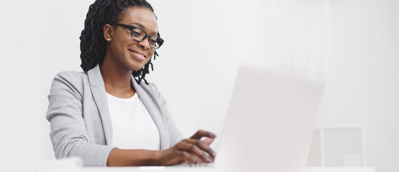 An office employee black lady is focused on her computer at her desk. The atmosphere is professional and modern, with a clean desk and bright space, highlighting concentration. photo