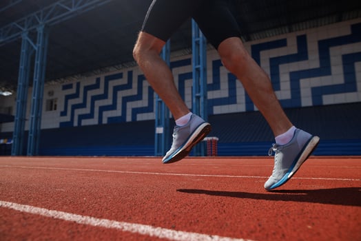 Runner's legs in motion on red track at outdoor stadium photo