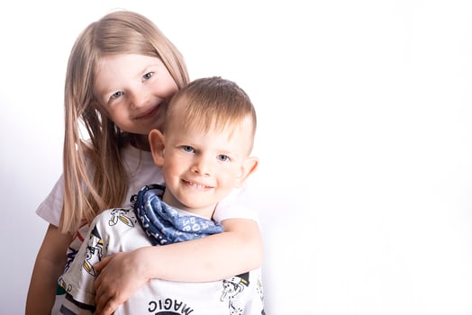 Two happy little children - sister and brother smile and hug on a light white background photo