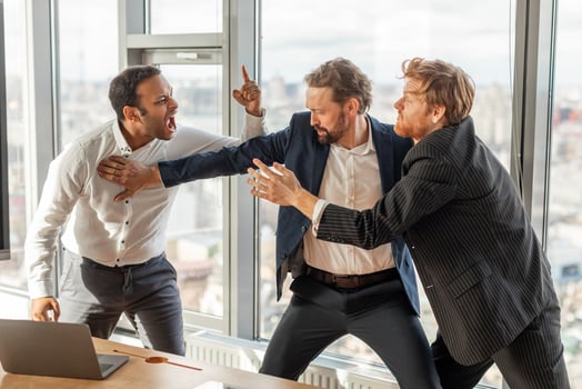 Three men in suits are engaged in a heated argument in a modern office setting. The man in the white shirt is yelling at the man in the blue suit, who is pushing him away photo