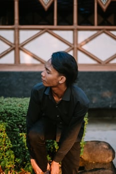 A Southeast Asian man is standing while putting on his shoes photo