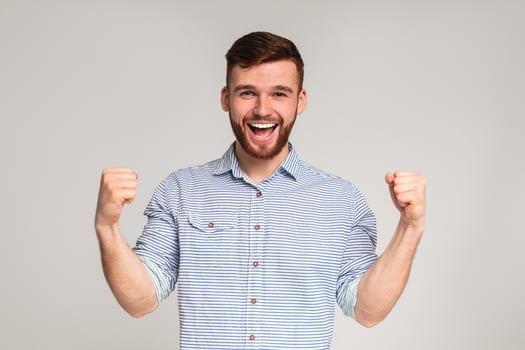 Cheerful guy showing his biceps, gesturing hands up and smiling on grey studio background, copy space photo