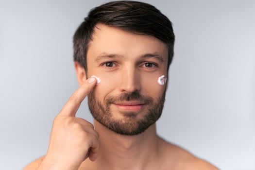 Skincare. Middle Aged Man Applying Anti-Aging Cream On Face Skin Over White Background. Studio Shot, Isolated photo