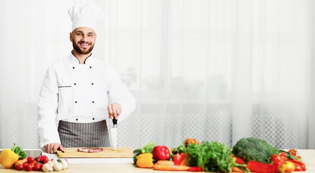 Chef Man Cooking Fresh Meat Steak Posing Holding Knife Smiling At Camera Standing In Kitchen Indoor. Selective Focus photo