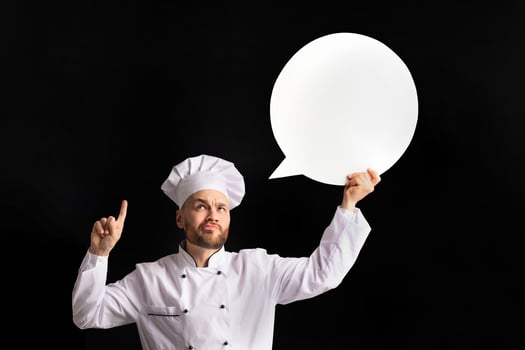 Funny Chef Man Holding Empty White Speech Bubble Pointing Finger Up Having Idea Posing Over Black Background. Studio Shot, Mockup photo