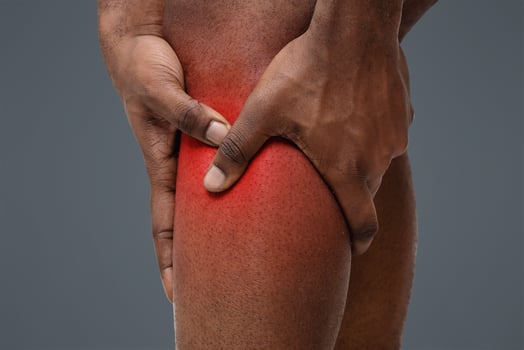 Sport trauma. Cropped of black man massaging his sore injured leg, white background photo