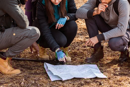 Confused group of multiethnic hikers looking at map, lost in forest photo