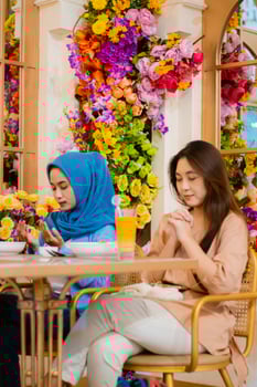 portrait of diversity 2 beautiful adult asian woman praying devoutly before eating sitting on chairs in an indoor restaurant. for the concept of religion, lifestyle, worship, advertising photo