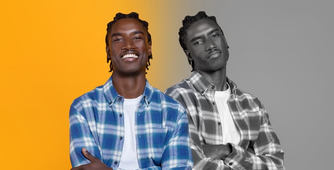 A young black man stands confidently, smiling broadly while wearing a plaid shirt over a t-shirt. He is positioned between two contrasting backgrounds, one vibrant yellow and the other in monochrome photo