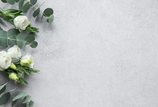 Delicate arrangement of mixed flowers and eucalyptus leaves on a light grey surface photo