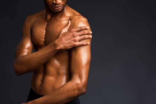 Naked Torso. Cropped image of afro guy touching his muscular body over black studio wall with copyspace photo