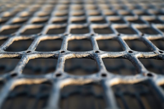 Close-up view of a textured metal grid showing patterns and shadows in natural light photo