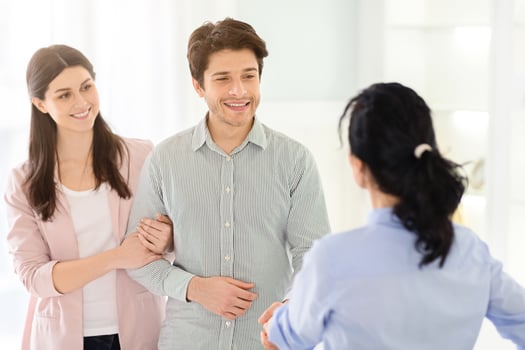A couple is engaging in a handshake with a woman family counselor in an office setting. The couple and the psychologist are standing and facing each other photo