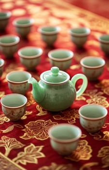 A green tea pot and several cups on a red table photo