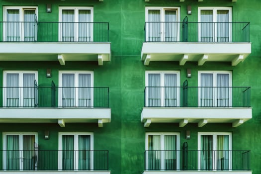 Bright green facade of old building or hotel with windows and balconies. City architecture minimalist concept. Minimal pattern building background. photo