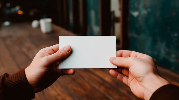Two hands holding blank card mockup outdoors on wooden counter. Natural rustic atmosphere. Voucher coupon template advertising image. Businesscard mock up product photorealistic photo