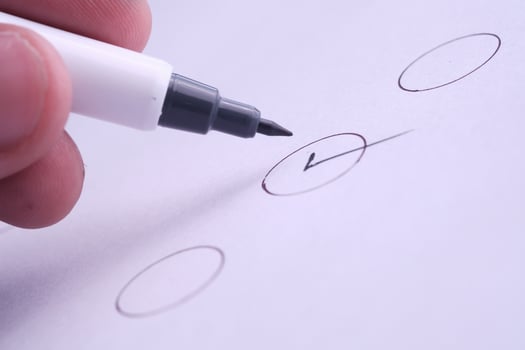 A hand grasping a pen, diligently marking a checklist on a piece of paper thoughtfully photo
