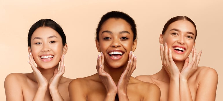 Facial Skincare. Three Beautiful Diverse Girls Posing Touching Face Perfect Skin Smiling At Camera Standing Over White Studio Background. Panorama photo