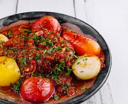 Spicy beef stew garnished with fresh herbs and vegetables on rustic plate photo