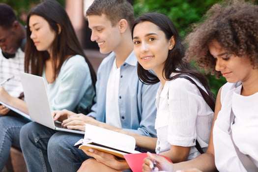 Exams Preparation. Group Of Multi-Ethnic Students Studying Together Outdoors, Selective Focus On Arabic Girl With Notepad photo