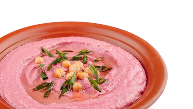 Beetroot hummus decorated with chickpeas and green onions in a clay dish photo