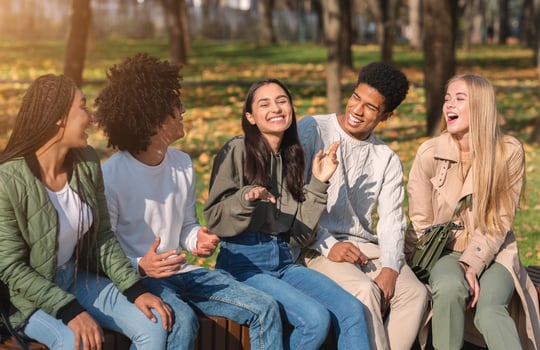 Group of international teenagers having fun in public park, talking and laughing photo