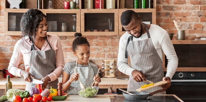 African mom and daughter watching dad while cooking together at home, panorama with copy space photo