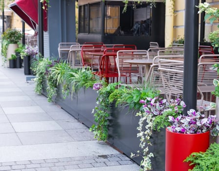 Outdoor landscaping - pots and planters on the city street with outdoor flowers violets, marigolds, ivy. Decoration of cafes, windows of the house with flowerbeds with flowering plants photo