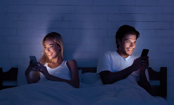 Young Spouses Using Phones Lying In Bed Ignoring Each Other At Night Indoor. Modern Relationship Issues. photo
