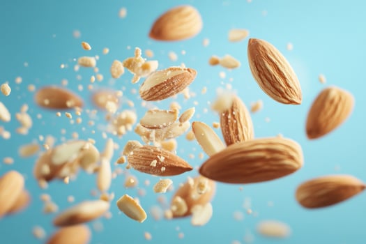 Shelled almonds crushed and flying on blue background photo