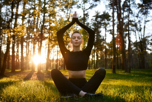 A woman is engaged in yoga meditation at sunrise, surrounded by nature in a forest setting photo