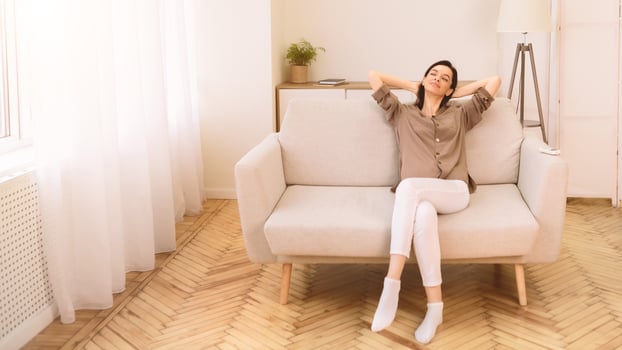 Free Of Stress. Portrait of happy girl relaxing on sofa after work at home, lying in the living room, copyspace, panorama photo