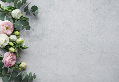Delicate arrangement of mixed flowers and eucalyptus leaves on a light grey surface photo