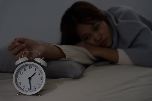 asian woman in bed late trying to sleep suffering insomnia, sleepless or scared in a nightmare, looking sad worried and stressed. Tired and headache or migraine waking up in the middle of the night. photo