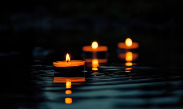 Multiple candles floating gently on a dark lake photo