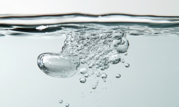 Dissolving pill in clear water, bubbles rising, close-up photo