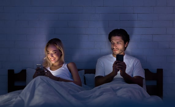 Infidelity Concept. Unfaithful Girlfriend Chatting On Phone Lying With Boyfriend In Bed At Night. Low Light, Selective Focus photo