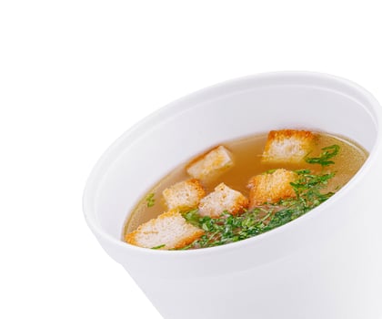 Delicious broth with croutons in a white bowl on white background photo