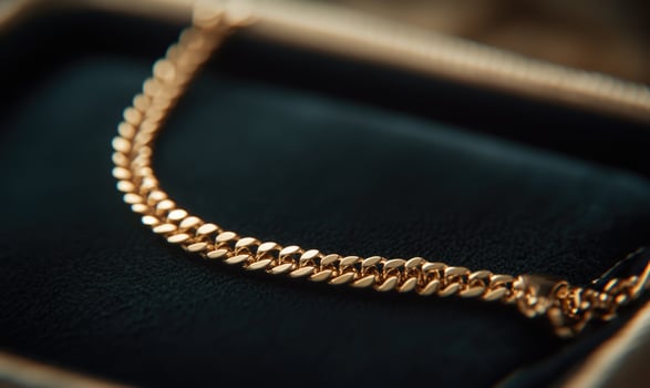 A gold chain necklace is displayed in a black velvet box photo