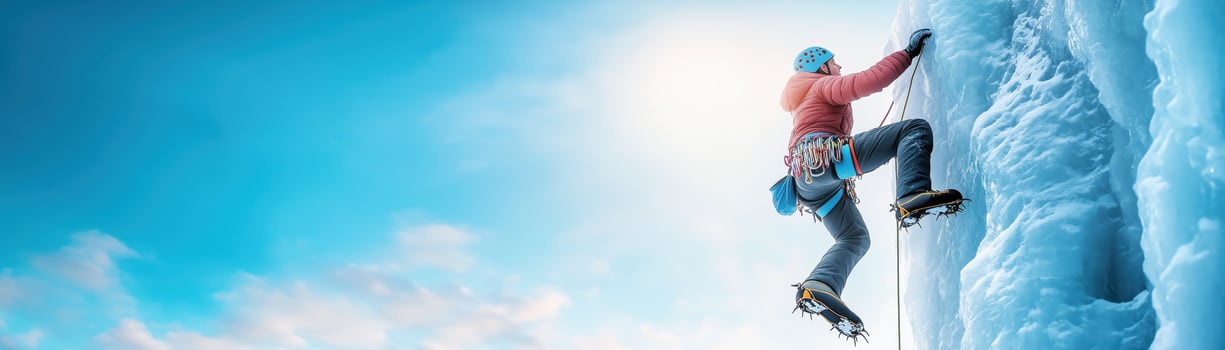 A climber ascends a massive ice wall under a bright blue sky, showcasing adventure and determination in winter sports. photo