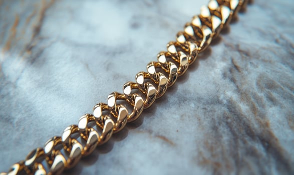 A gold chain with a clasp is on a marble surface photo