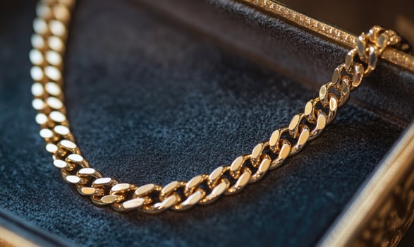 A gold chain necklace is displayed in a black box photo