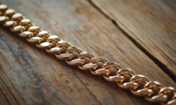 A gold chain with a clasp is on a wooden surface photo